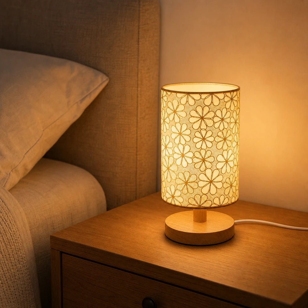 Luminária de mesa floral com base de madeira acesa em luz quente sobre mesa de cabeceira