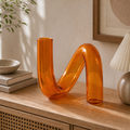 Vaso decorativo irregular de vidro translucido laranja em ambiente premium