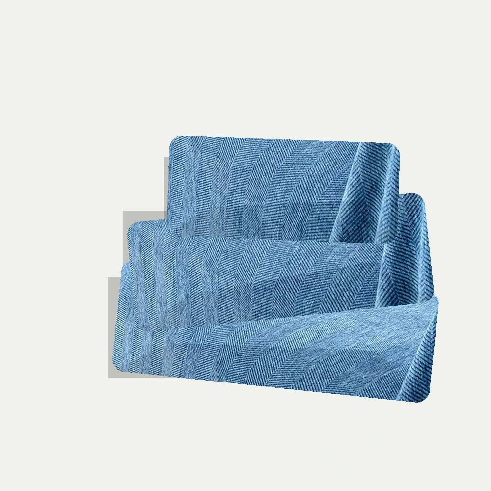 Capa de sofá azul dobrada com textura em espinha sobre fundo neutro