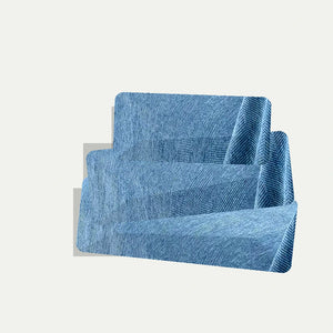 Capa de sofá azul dobrada com textura em espinha sobre fundo neutro