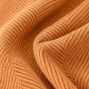 Detalhe da textura real da manta para sofá laranja