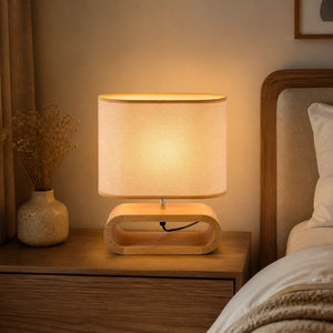 Luminária de mesa com base de madeira nórdica e cúpula de tecido acesa em quarto elegante