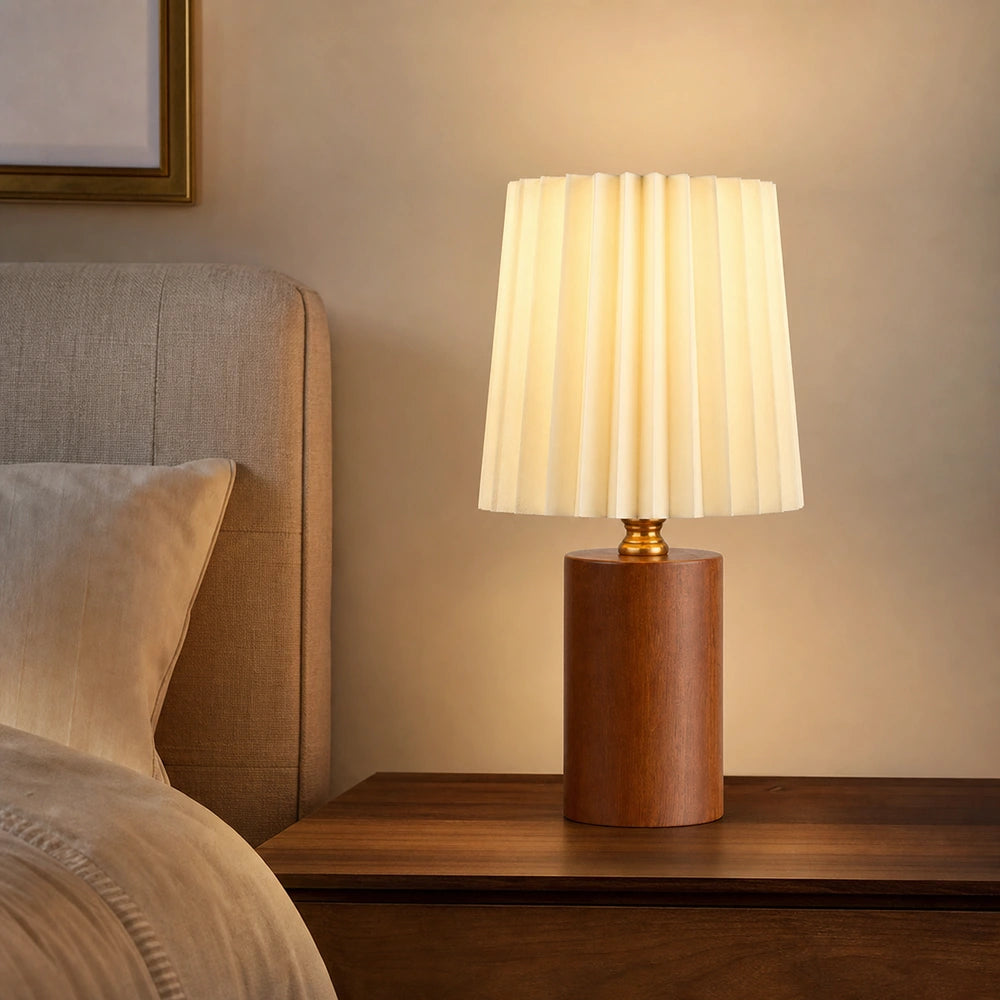 Luminária de mesa com base de madeira marrom e cúpula plissada no quarto